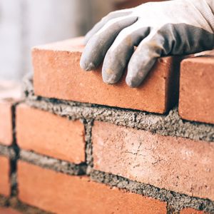 Close up of industrial bricklayer installing bricks on construction site